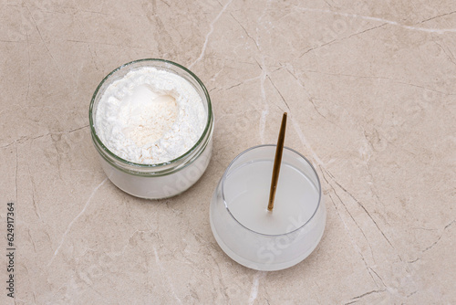 Glass of water and a jar of collagen goodnesson a marble beige background.