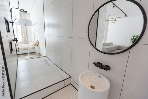 fashionable stylish shower area in a minimalistic modern luxury design of an expensive house on a sunny day in white with a round mirror and a floor sink
