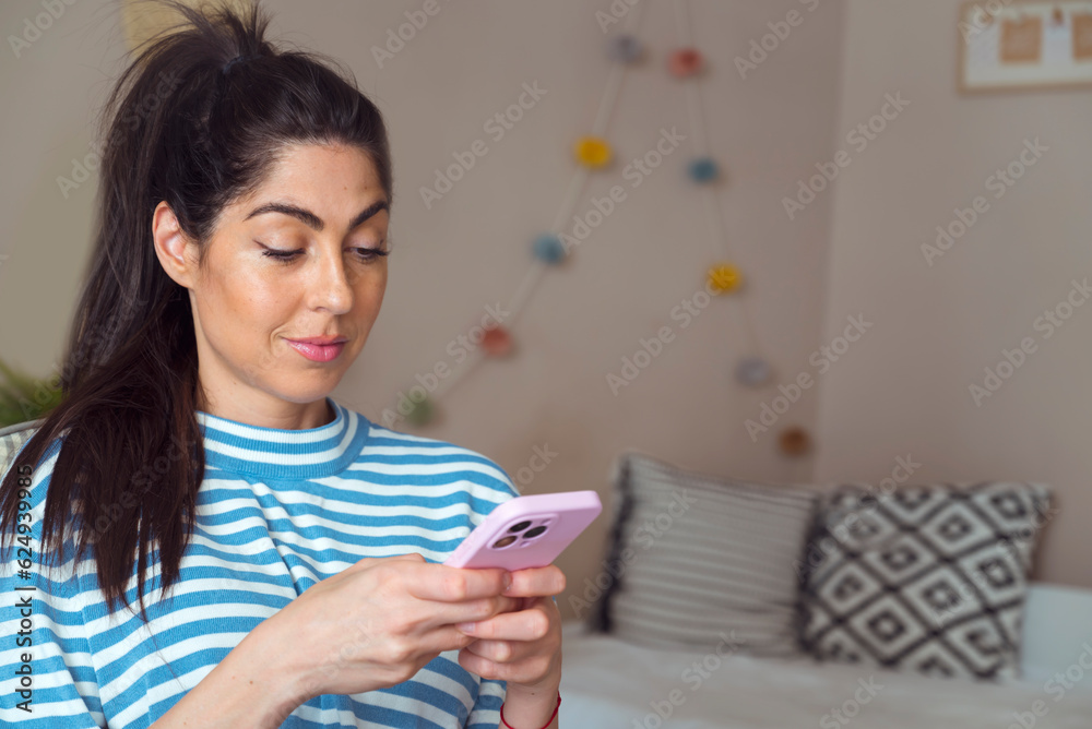 Beautiful young happy woman sitting at home and using mobile phone Beautiful young happy woman sitting at home and using mobile phone