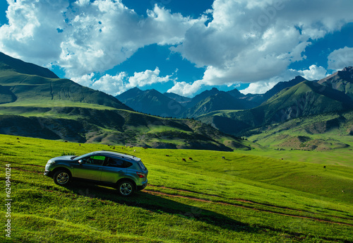 Modern car on a green hill in a picturesque mountains valley, travel concept