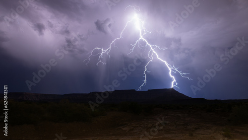 A bolt of lightning splits into several branches as it flashes in the stormy night sky above Gooseberry Mesa in Southern Utah during a summer Monsoon storm.