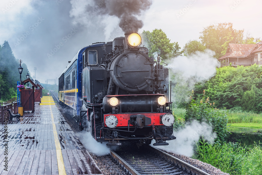 Obraz premium Retro steam train approaches to the platform.