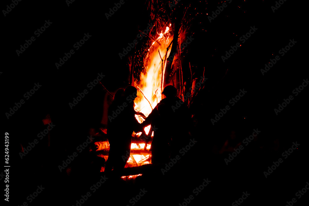People against a bright high red flame at night People against a bright high red flame at night