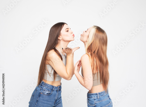 Two cheerful young female friends laugh and rejoice, have fun together.