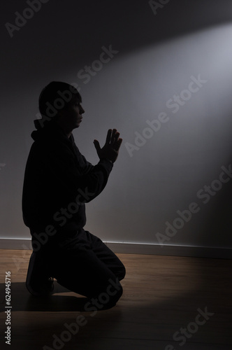 homem de joelhos fazendo oração sozinho recebendo luz 