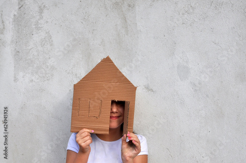 criança brincando com casinha de papelão, sonho da casa própria, negócios imobiliários, casa em contrução e financiamento da casa própria photo