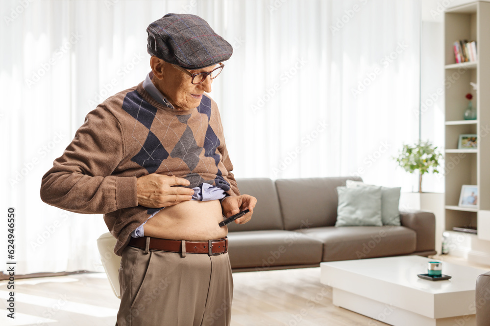 Elderly man poking abdomen with an insulin pen at home Elderly man poking abdomen with an insulin pen at home