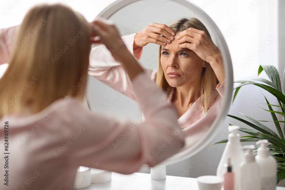 Stressed Mature Lady With Pimple On Forehead Looking In Mirror At Home Stressed Mature Lady With Pimple On Forehead Looking In Mirror At Home