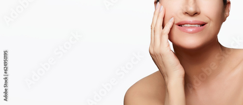 Skincare concept. Middle-aged woman with a beautiful complexion, gently touching her hydrated skin