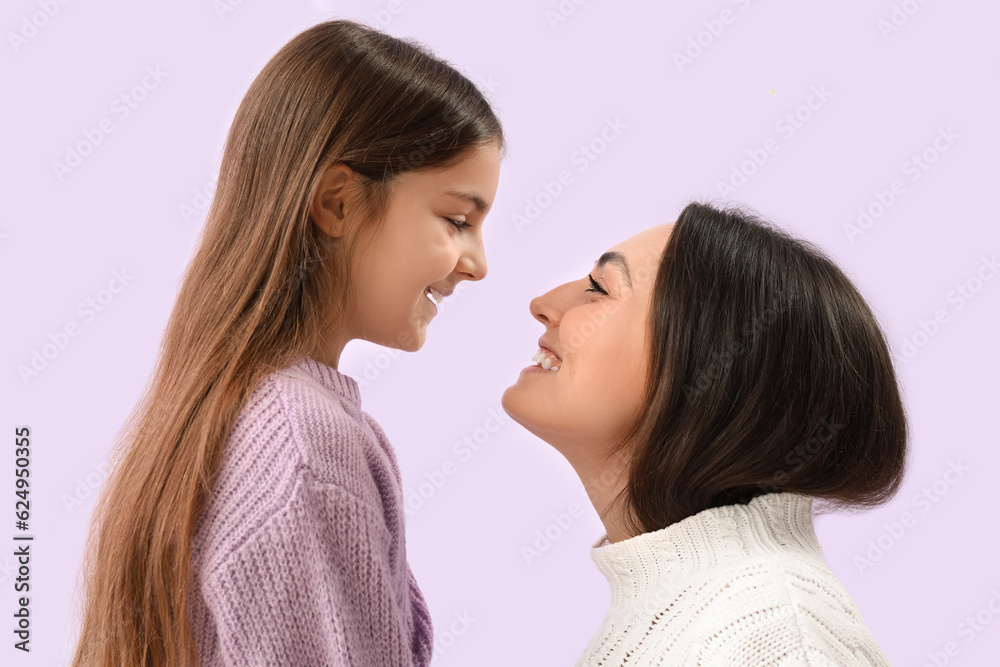Little girl and her mother in warm sweaters on lilac background, closeup Little girl and her mother in warm sweaters on lilac background, closeup
