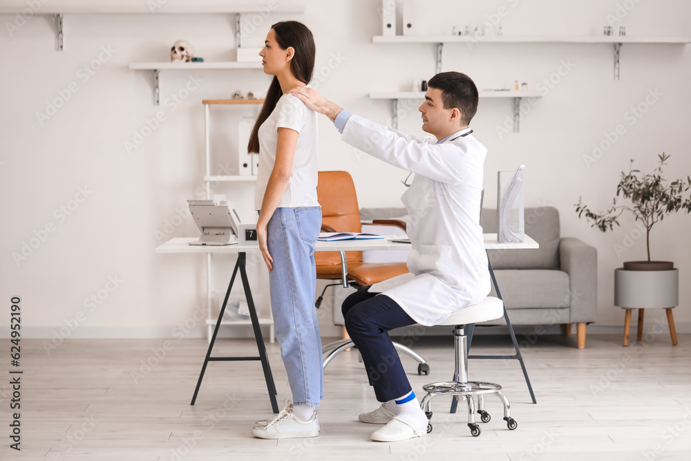 Male doctor checking posture of young woman in clinic