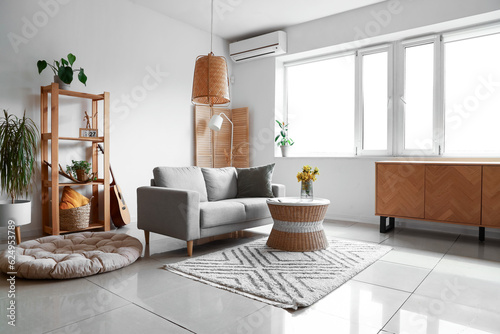 Interior of light living room with grey sofa  shelving unit and window