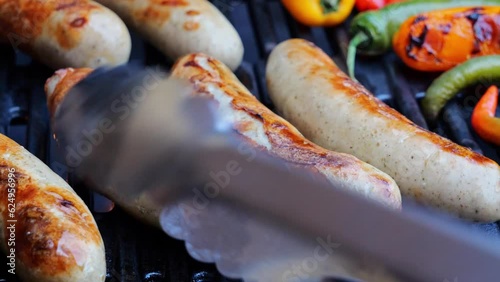 Cooking roast juicy bratwurst sausages on the barbecue grill. Close up.