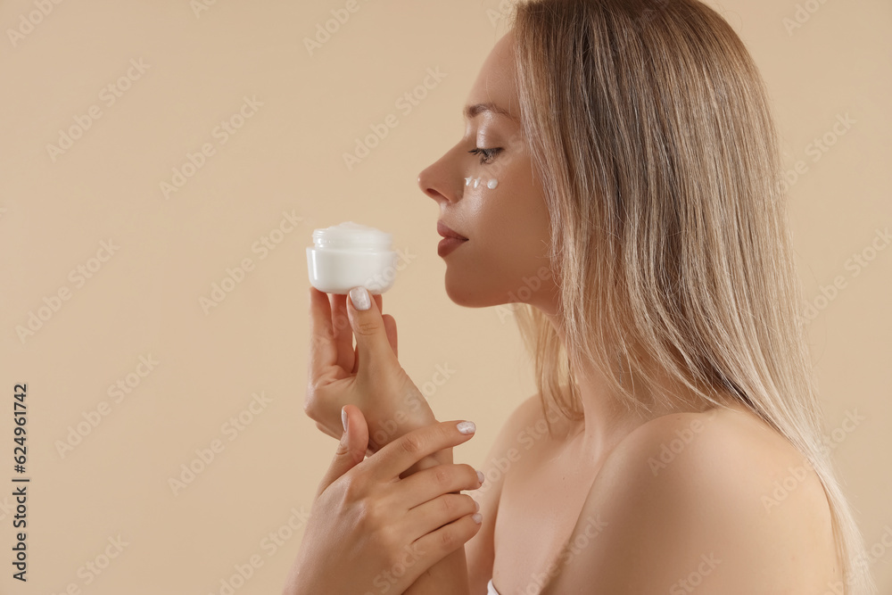 Pretty young woman with facial cream on beige background Pretty young woman with facial cream on beige background