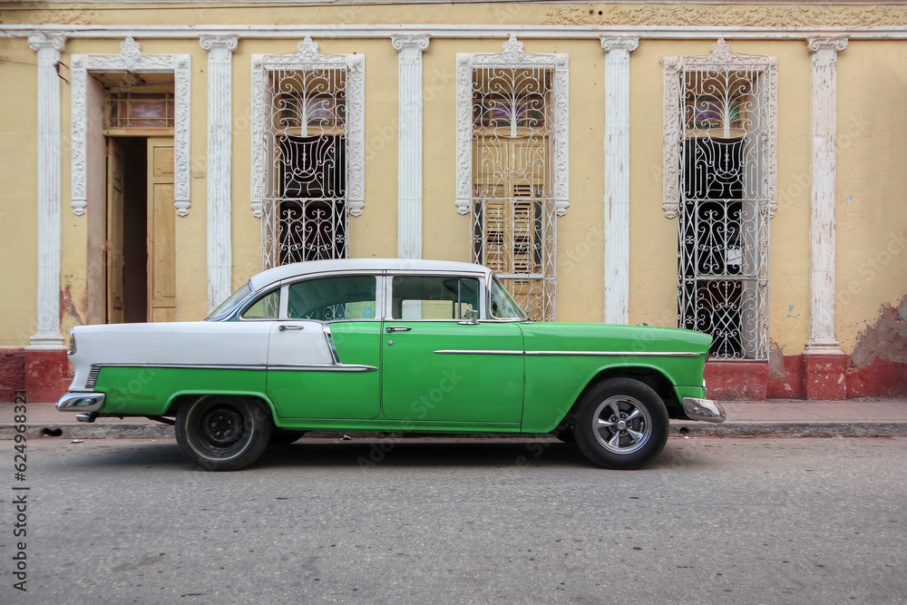 A green Cuban taxi in front of a light orange facade in the town of Trinidad 