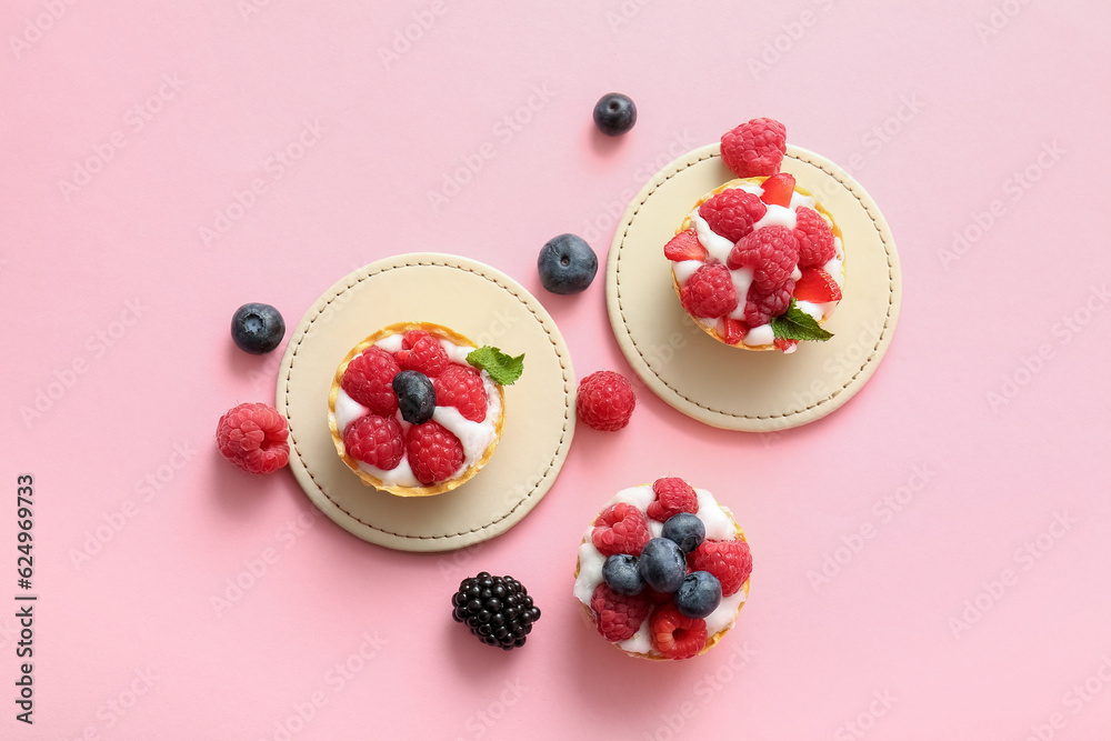 Tasty tartlets with whipped cream and berries on pink background Tasty tartlets with whipped cream and berries on pink background