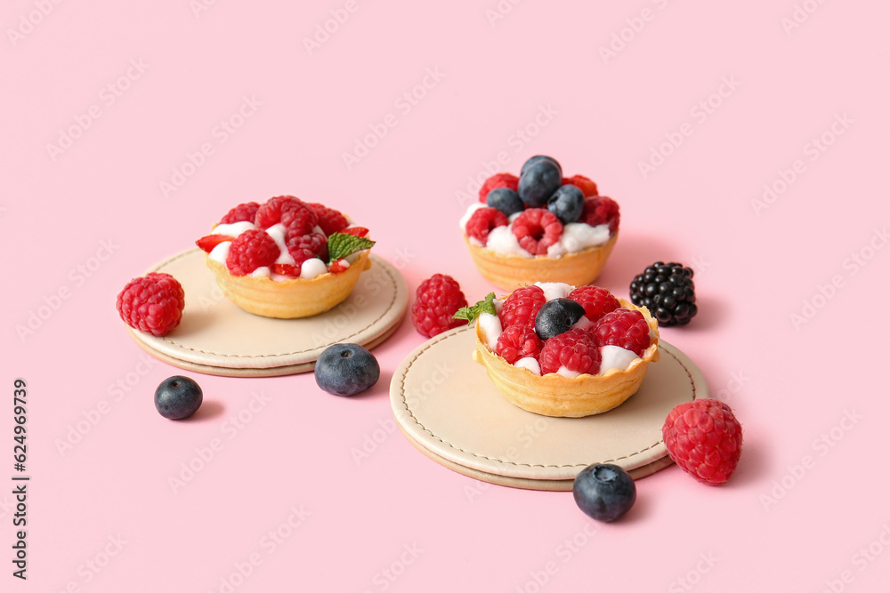 Tasty tartlets with whipped cream and berries on pink background Tasty tartlets with whipped cream and berries on pink background
