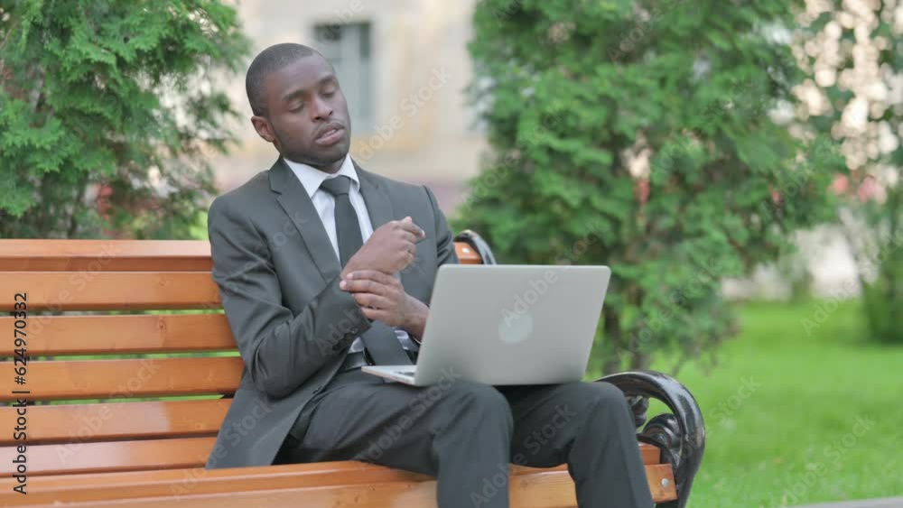 African Businessman with Wrist Pain Working on Laptop Outdoor African Businessman with Wrist Pain Working on Laptop Outdoor