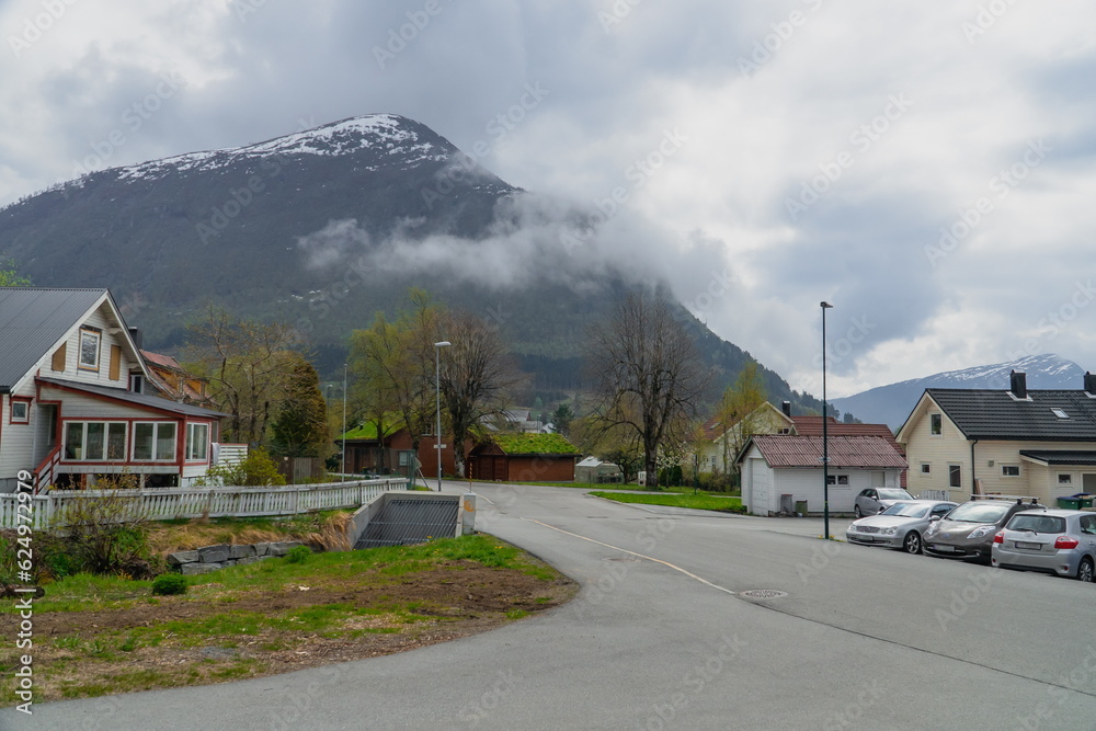 View of small town in Norway against backdrop of mountain in cloudy weather