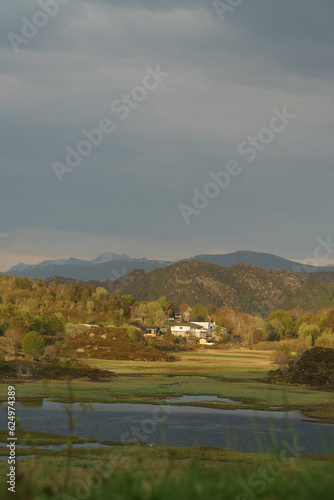 View of village in Norway surrounded by mountains at sunset after rain