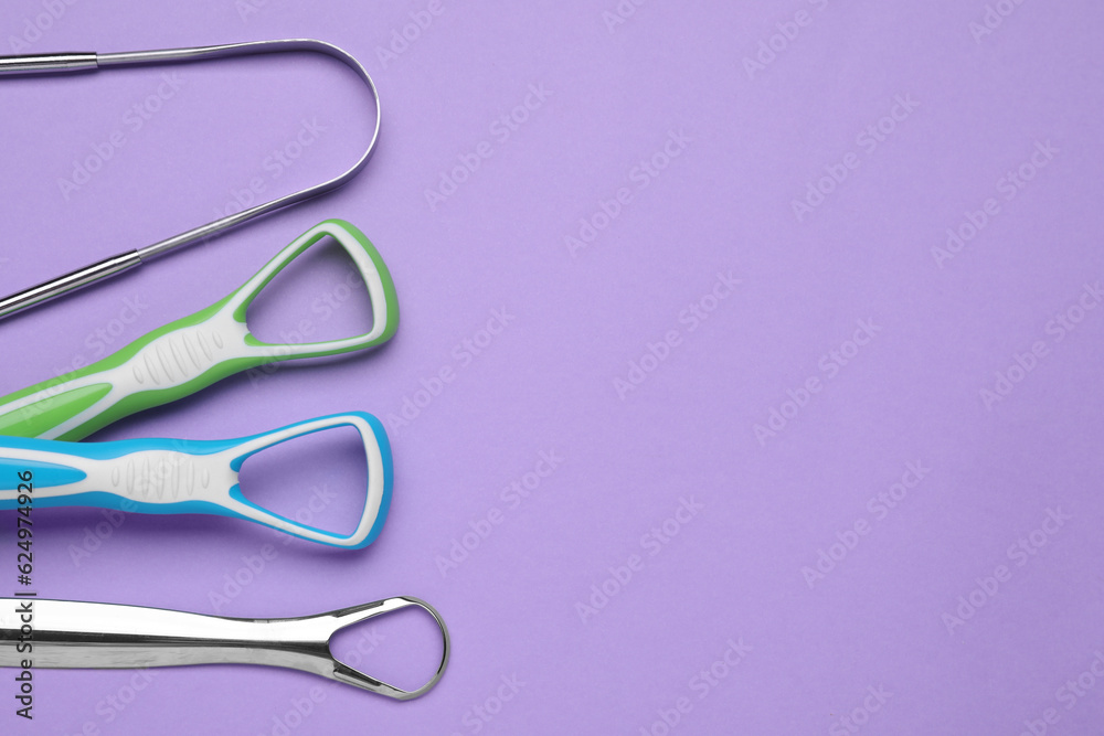 Different tongue cleaners on violet background,flat lay. Space for text Different tongue cleaners on violet background,flat lay. Space for text
