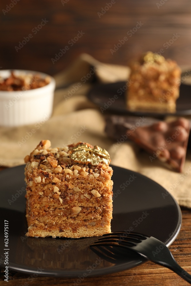 Piece of honey cake with walnuts and fork on plate, closeup Piece of honey cake with walnuts and fork on plate, closeup