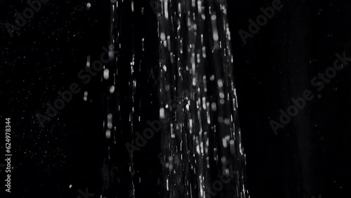 Running water from a shower head pouring down on a black background