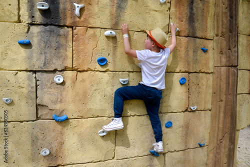 The boy is engaged in rock climbing.
