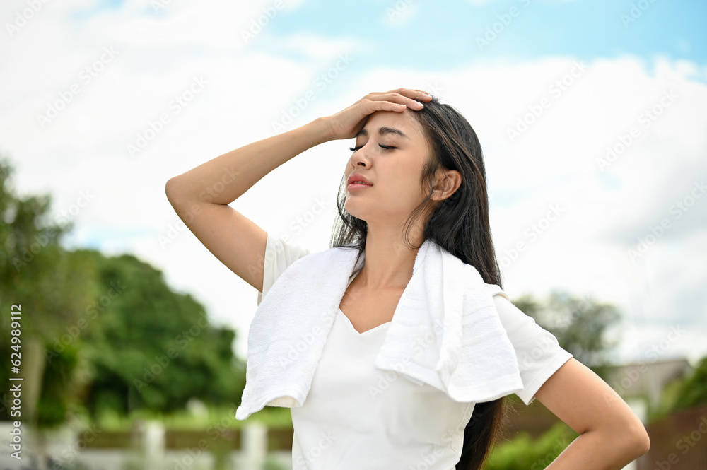 A tired young Asian woman in sportswear rests after a long run at the park on the weekend. A tired young Asian woman in sportswear rests after a long run at the park on the weekend.