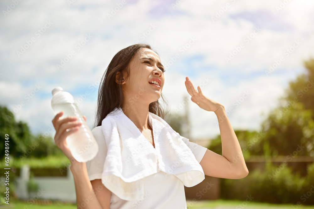 A tired Asian womanis fighting the heat wave while running in a park on a summer day. A tired Asian womanis fighting the heat wave while running in a park on a summer day.