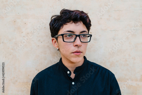Close up view of a young transgender man looking on a wall.
