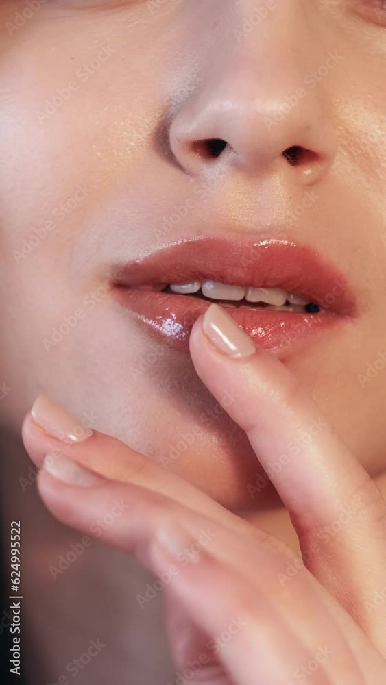 Vertical video. Lips makeup. Beauty trends. Plumping gloss. Care balsam. Woman with curvy puffy mouth in juicy lipstick with hand touching glowing radiant face skin. Vertical video. Lips makeup. Beauty trends. Plumping gloss. Care balsam. Woman with curvy puffy mouth in juicy lipstick with hand touching glowing radiant face skin.