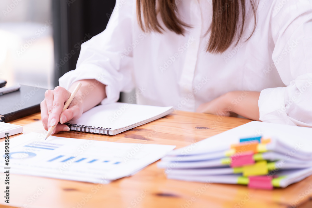 Hand of a businesswoman working with papers and documents at a desk in the office. Hand of a businesswoman working with papers and documents at a desk in the office.