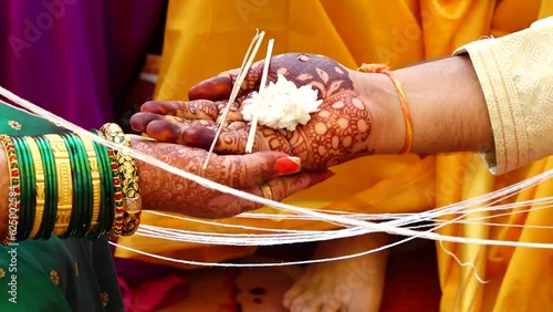 Hands of Hindu Bride and Groom holding white flower and sticks. Around White Thread. Marathi Wedding kanyadaan Ceremony Ritual. Maharashtra Culture. Indian Marriage