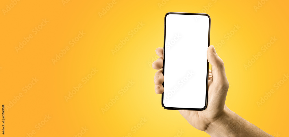 Hand holding black cellphone with blank screen and modern frame less design on yellow background. smartphone showing white blank screen in hand, . Gadget with empty free space for mockup, banner