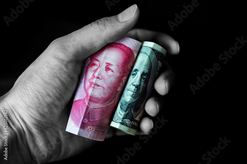Us dollar and Chinese yuan in hand isolated on black background