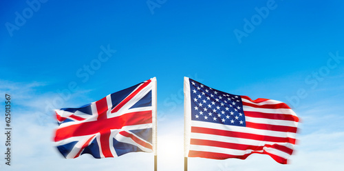 USA and Britain flags against blue sky background