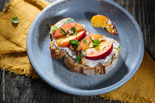 Spread with cream cheese on bread with rucola, nuts and peach. Healthy summer brunch. Vitamins and minerals