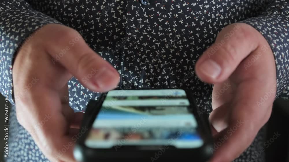Man use of mobile phone closeup. Hands of person quickly flipping through tape on Internet view on social network with fingers.