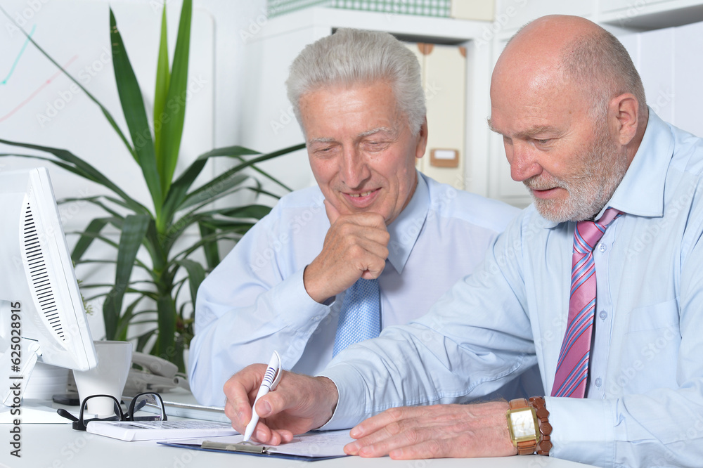 Two old business men sitting at desk and working Two old business men sitting at desk and working