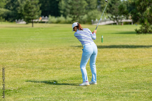 Professional woman golfer wearing golf wear teeing golf in golf tournament competition at golf course for winner.
