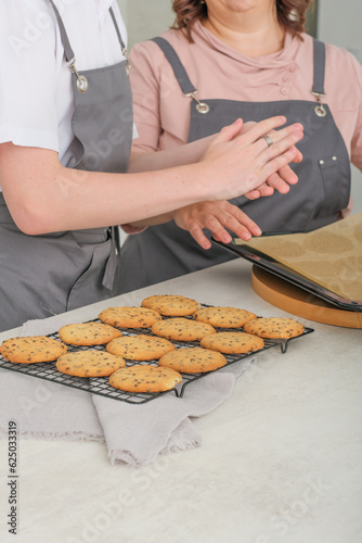 woman chef teaching how to cook her teenager son. making chocolate chip biscuits at home , family together spending time cooking at holiday.