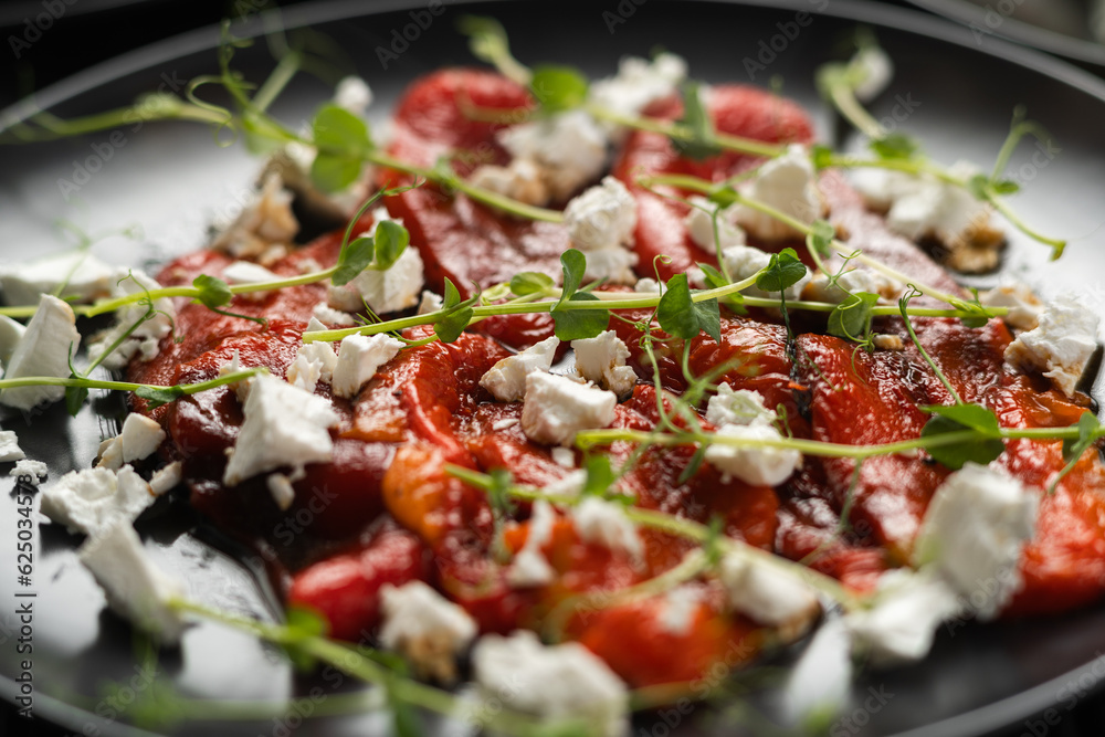 Baked red peppers with feta cheese and microgreens on a plate, close-up, macro Baked red peppers with feta cheese and microgreens on a plate, close-up, macro