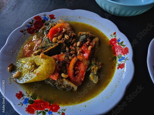 fish soup with various kinds of ingredients such us tomato, cucumber, peanut.