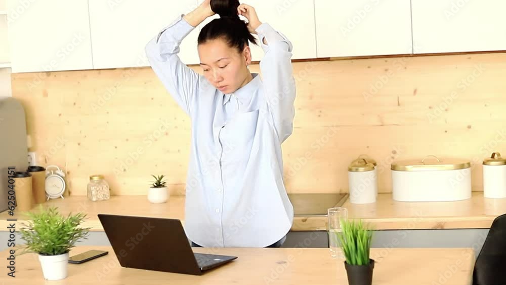 Asian girl works freelance remotely at home in the kitchen sitting at a laptop Asian girl works freelance remotely at home in the kitchen sitting at a laptop