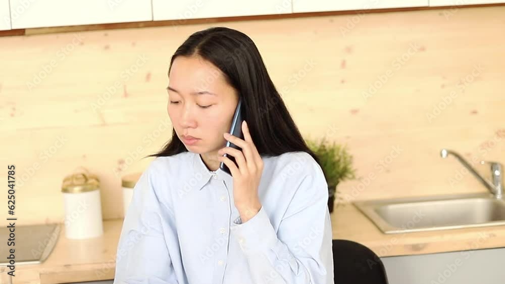 Asian girl works freelance remotely at home in the kitchen sitting at a laptop Asian girl works freelance remotely at home in the kitchen sitting at a laptop