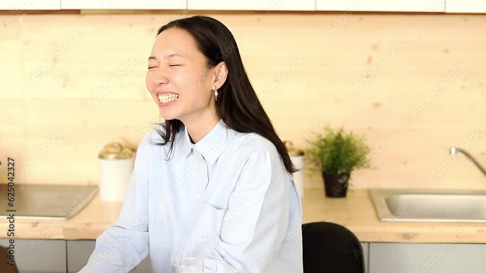 Asian girl works freelance remotely at home in the kitchen sitting at a laptop Asian girl works freelance remotely at home in the kitchen sitting at a laptop