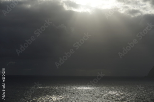 Morning and clouds over the Atlantic Ocean. Bright sunlight and glare on the water. Dark rainy sky