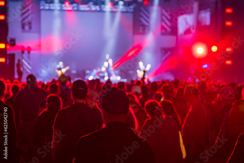 Unrecognizable crowd of people standing and listening to music of artists on stage in concert