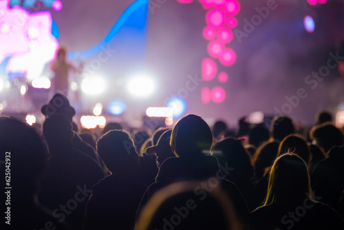 Unrecognizable crowd of people standing and listening to song of artist on stage in live concert